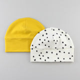 a mustard yellow baby hat behind a white hat with stars