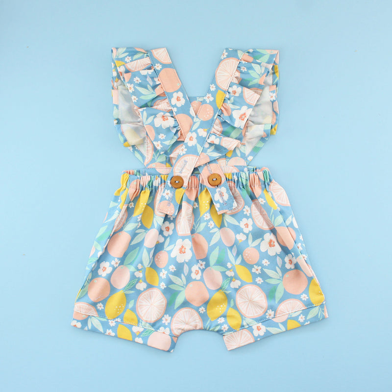 Back of Flutter Sleeve Rainy Day Romper In fruit Fabric on Bright Blue Background